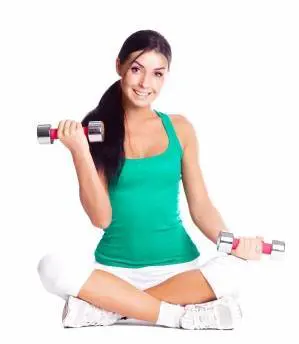Fitt nő törökülésben ülve kis súlyokkal edz