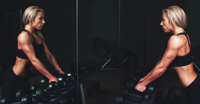 Nő edzőteremben súlyokkal a tükör előtt Nő edzőteremben súlyokkal a tükör előtt