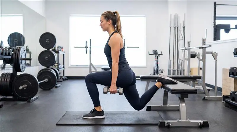 sportos lány edzőteremben bolgár guggolást végez