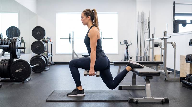 sportos lány edzőteremben bolgár guggolást végez